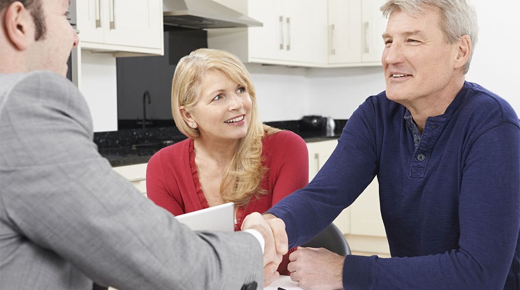 Attorney in kitchen shaking hands with sellers at closing.